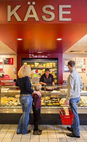 Family shopping at the cheese counter in the supermarket