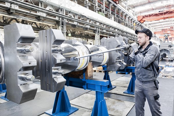 Employee tightening a screw plug on the crankshaft of a marine engine