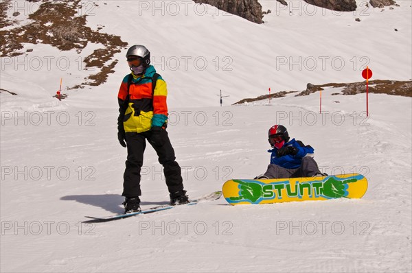 Two young snowboarders are preparing for a ski-run