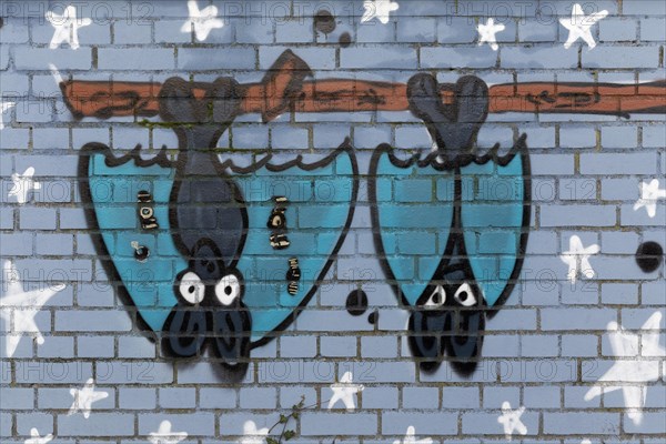 Two bat figures hanging upside down on a pole
