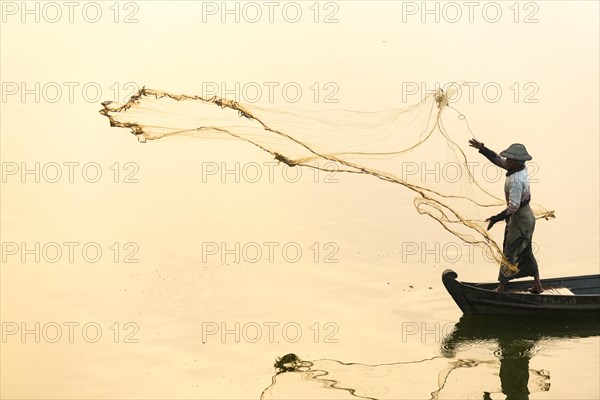 Fisherman in a boat tossing out a net