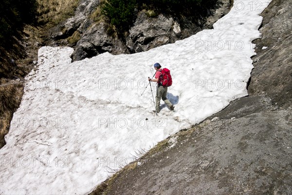 Female hiker crossing a snowfield on the Wilder-Kaiser-Steig hiking trail