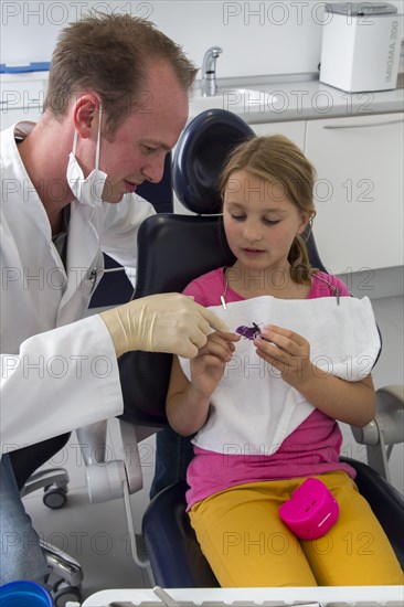 Dentist discussing further treatment with a girl and showing her braces