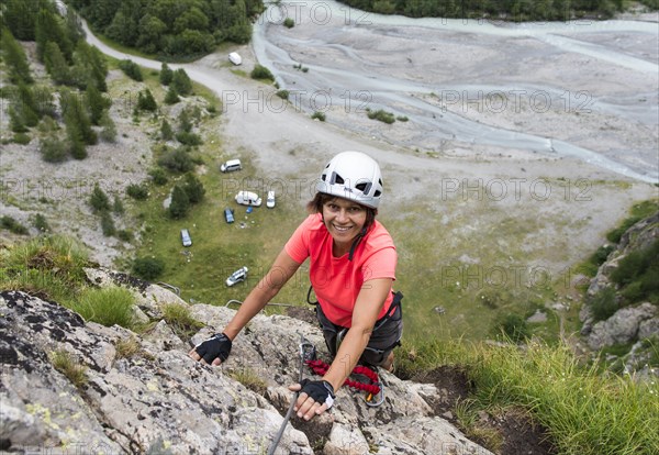 Female mountain climber climbing a fixed rope climbing route