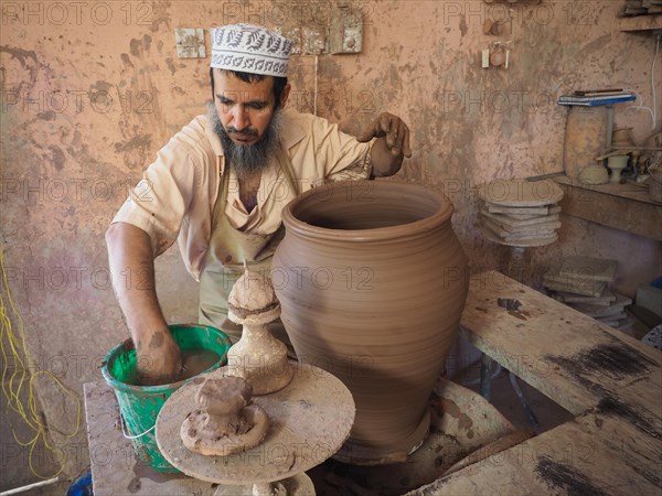 Potter makes pottery with potter's wheel a clay jug