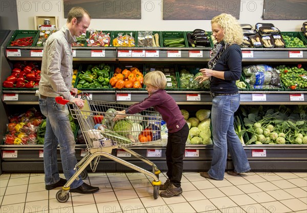 Family shopping with a shopping trolley in the fruit and vegetables department of a supermarket