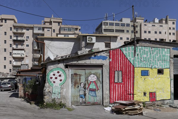 Brightly painted huts in front of modern residential buildings