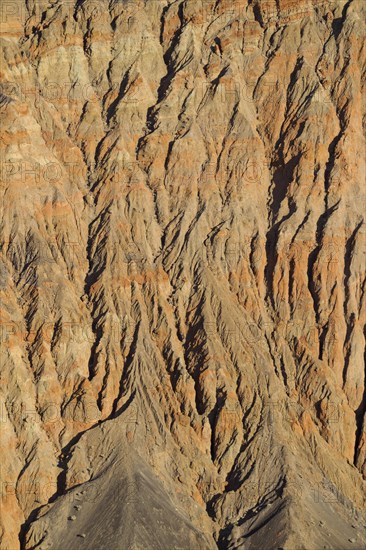 Exposed fissured bedrock of orange-colored conglomerate on the crater wall of Ubehebe Crater