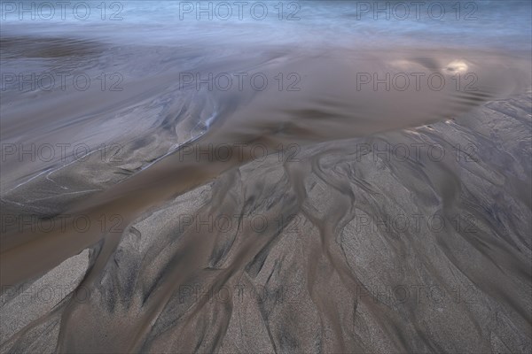 Water flows into the sea at the sandy beach