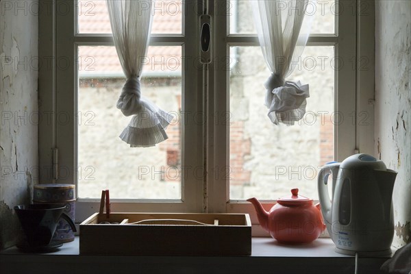 Water boiler and tea pot on kitchen window windowsill