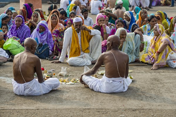 Two men and a pandit or priest are performing Dashkriya or Asthi Visarjan