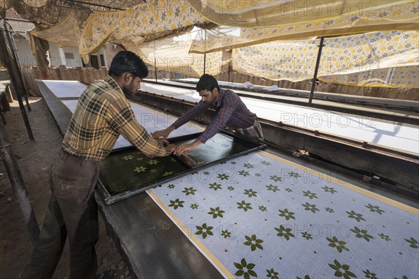 Men printing cloth by hand