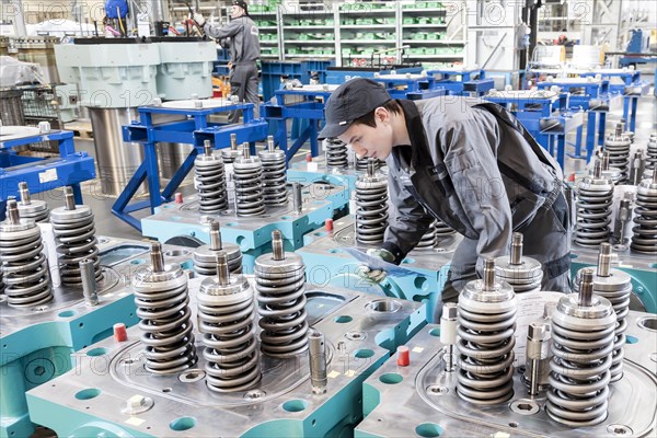 Employees checking cylinder heads for a marine engine