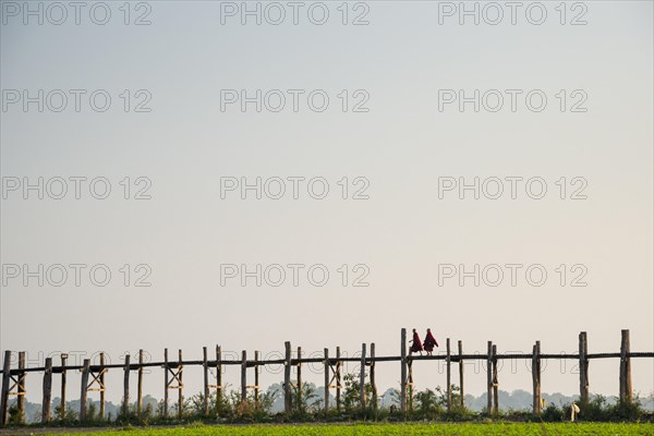 Monks walking on a teak bridge