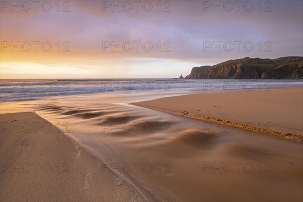 A brook flows over the sandy beach into the sea