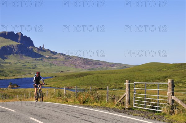 Cyclist on a road at The Storr with the The Old Man of Storr pinnacle