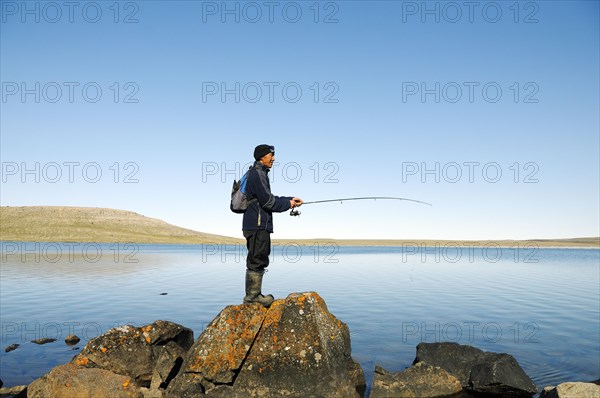 Men of the Inuit people fishing in a lake
