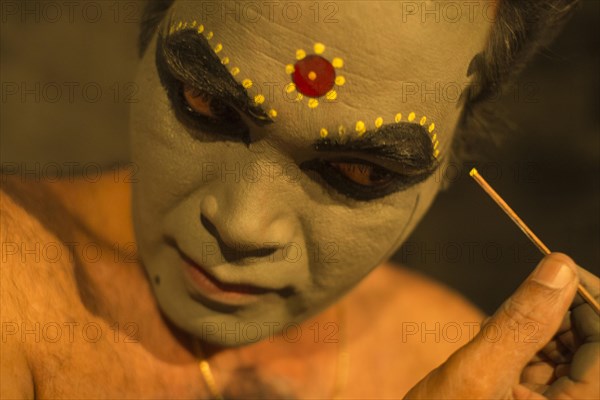 Kathakali dancer applying makeup in preparation for his performance