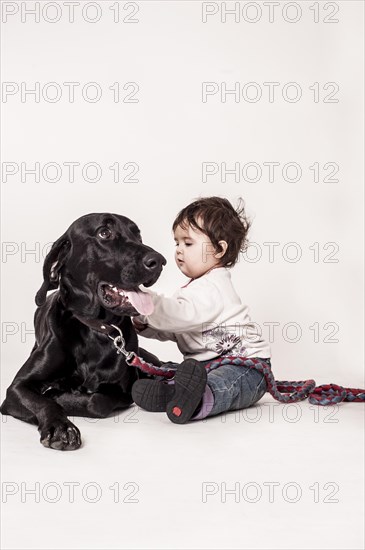 Big black mongrel lying next to a small child