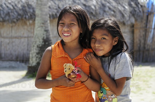 Two Kuna Indian girls holding a small soft toy