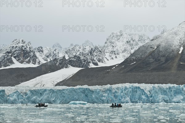 Tourists in rubber dinghies in front of the rim of the Monacobreen Glacier
