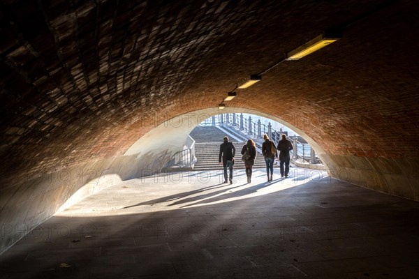 People in the light and shadow below the Liebknecht Bridge in Berlin Mitte