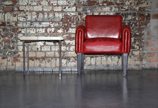 Red armchair in front of an old brick wall