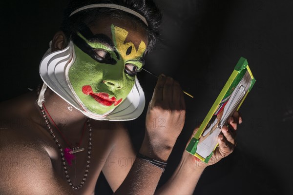 A Katakali artist is applying the make-up of the character Arjun for the Santhana Gopalam play during a temple festival