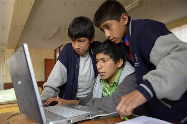 Three boys in a children's home are working together on a laptop