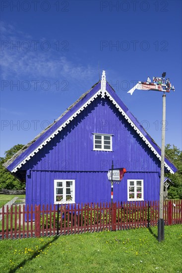 Curonian flag in front of a traditional wooden house