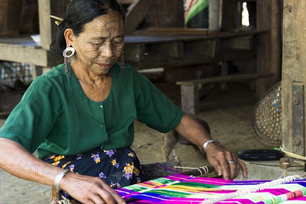 Woman with traditional facial tattoos and ear jewellery from the Chin people