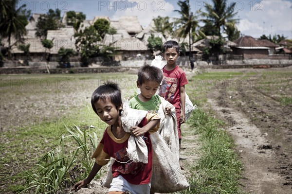 Indonesian children carrying sacks