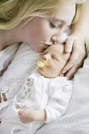 Big sister kissing her newborn brother