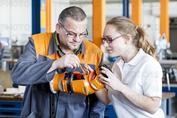 Instructor explaining a robot hand to a trainee for mechatronics assembly work