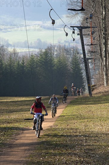 Mountain bikers are pulled by a ski lift