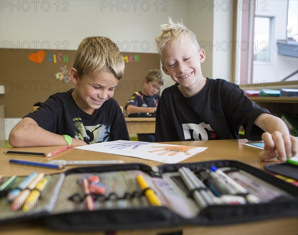 Smiling children sitting in a primary school class during a drawing lesson