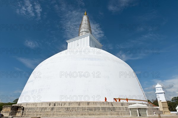 Monks tying a cloth around a large white stupa