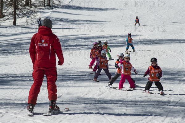 Children ski lessons with instructor on the piste