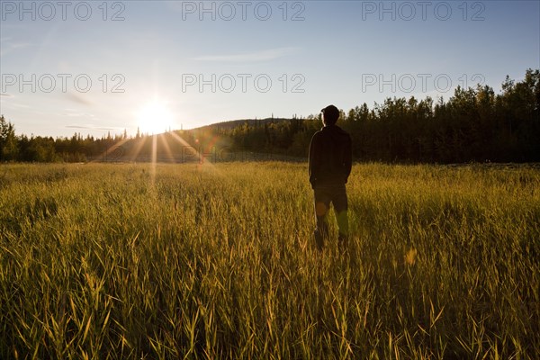 Man standing in a field at sunset