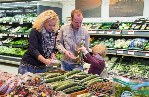 Family shopping with a shopping trolley in the fruit and vegetables department of a supermarket