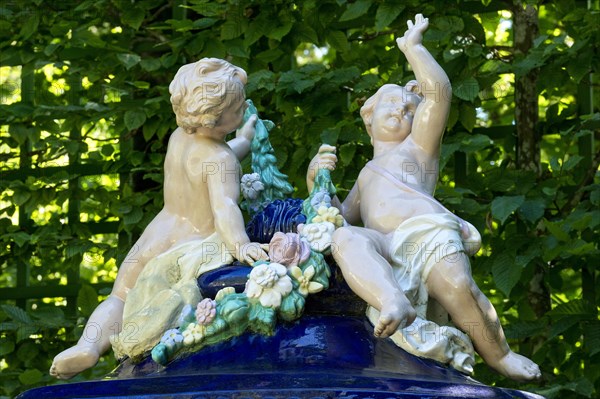 Putti on an ornamental vessel made of glazed ceramic