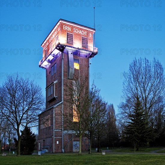 The illuminated Hammerkopfturm tower of Zeche Erin Colliery at dusk