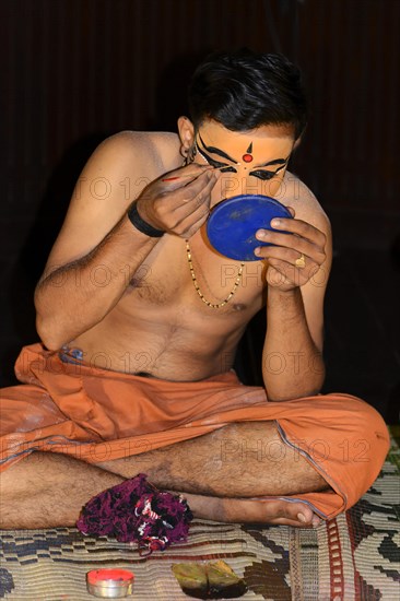 Kathakali dancer applying makeup in preparation for his performance