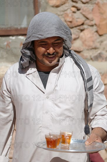 Modern Bedouin man carrying a tray with tea