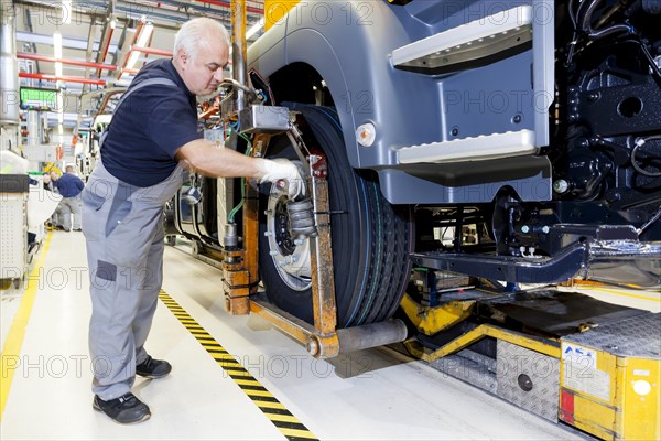 Employee mounting a tyre on a chassis at MAN Truck and Bus AG