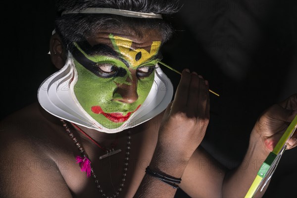 A Katakali artist is applying the make-up of the character Arjun for the Santhana Gopalam play during a temple festival