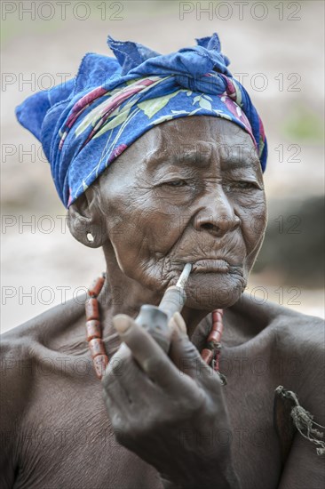 An elderly woman from the Koma people smoking a pipe