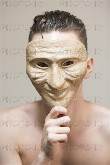 Man hiding behind a happy mask