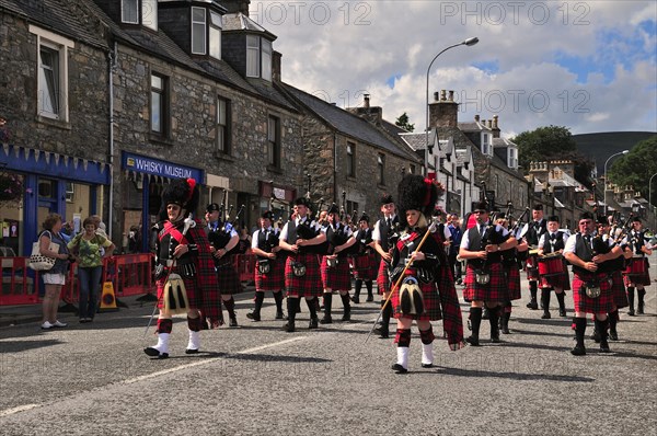 Pipe major leading a pipe band marching in unison through the town