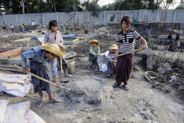 Children and teenagers mix concrete on a high rise construction site